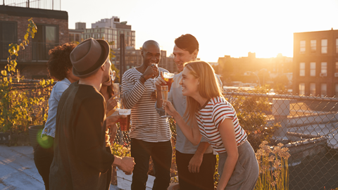 a group of people standing on a rooftop talking and drinking wine